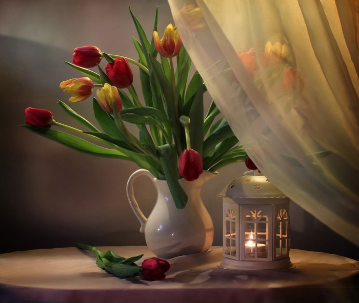Tulips in a vase with a candle lantern
