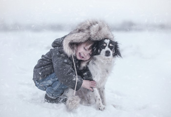 Boy hugging a dog in the snow