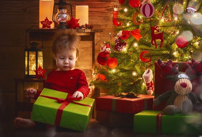 Baby opening Christmas gift by tree