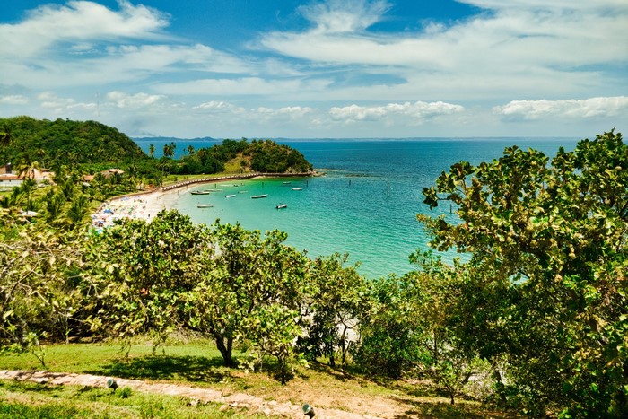 Tropical beach with boats and lush green hills