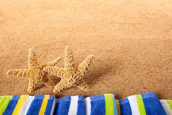 Two starfish on a sandy beach with a striped towel
