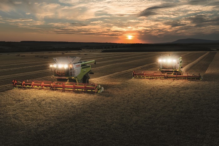 Two Claas Lexion 780 combine harvesters in a field at sunset