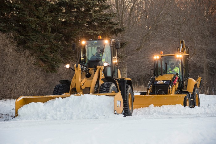 Two Caterpillar loaders clearing snow