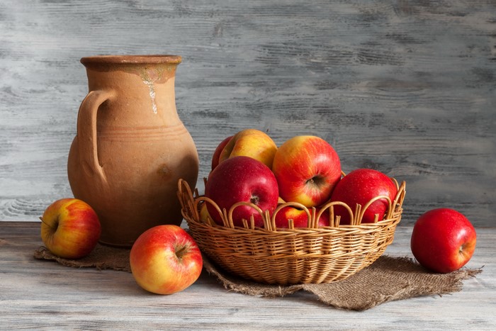 Apples in a wicker basket with a jug