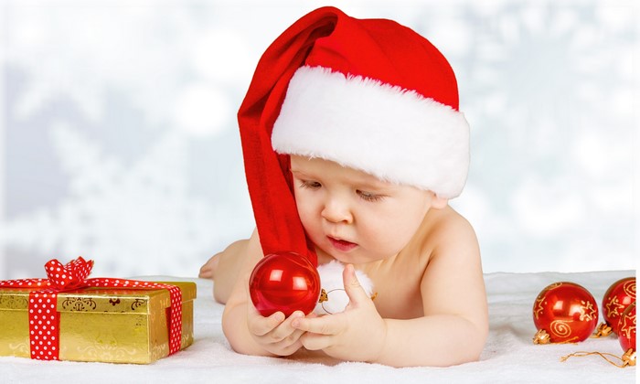 Baby in Santa hat with Christmas ornaments and gift