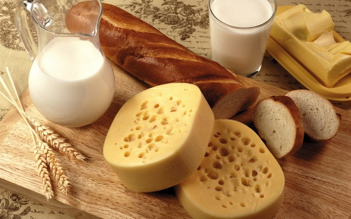 Cheese, Milk, Bread, Butter, and Wheat on a Wooden Board