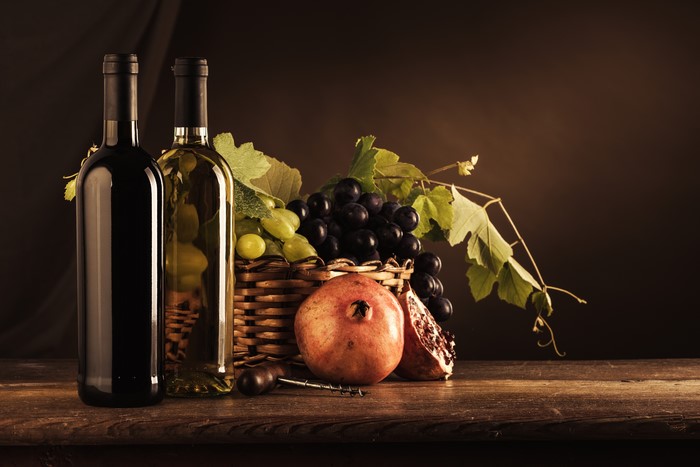 Still-life with wine bottles, grapes, and pomegranate