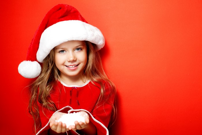 Little girl in Santa hat holding snow