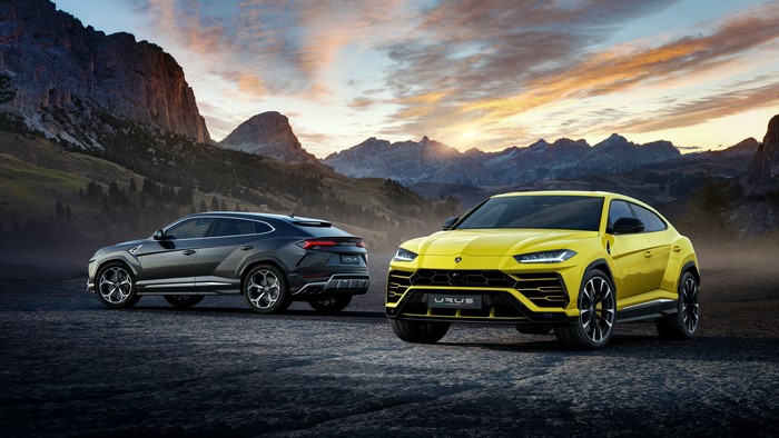 Two Lamborghini Urus SUVs in a mountain landscape