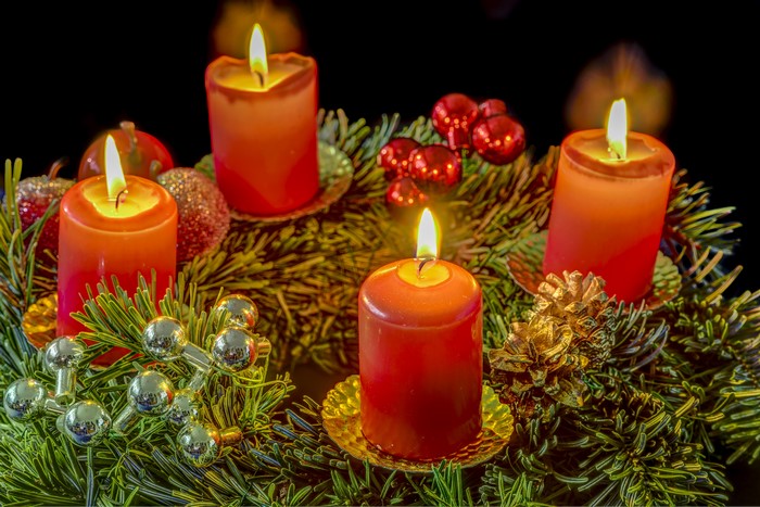 Four lit Christmas candles on a wreath