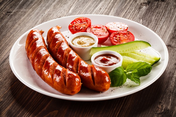 Sausages with Tomatoes, Cucumbers, and Dips on a Plate