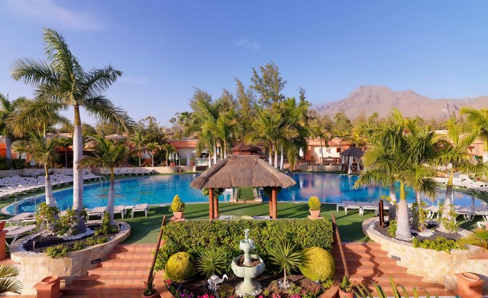 Resort pool with palm trees and mountains in Tenerife, Spain