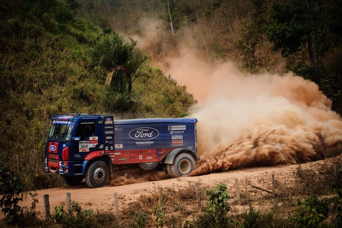 Ford truck racing on a dirt road kicking up dust