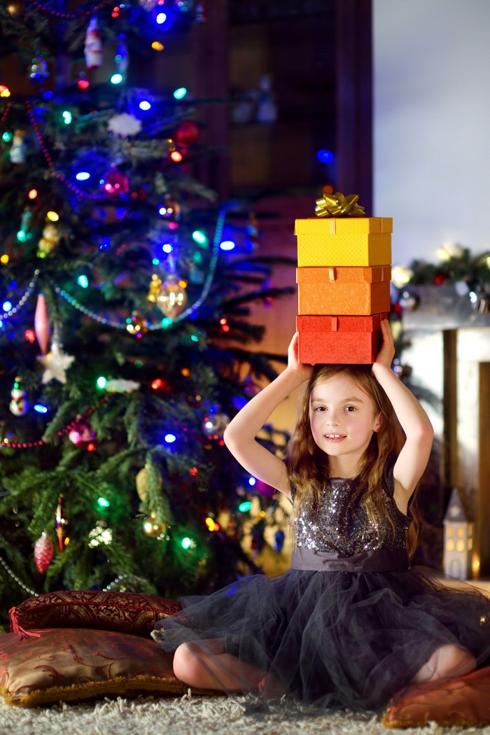 Girl with gifts near Christmas tree