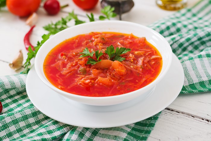 Borscht soup in a white bowl on a plate