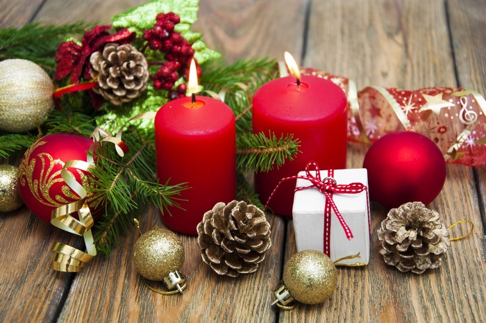 Christmas candles with ornaments and pine cones on wood