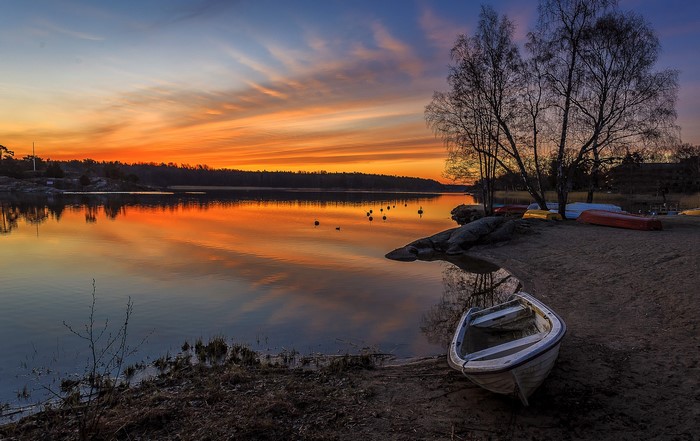 Sunset over a lake with boats on the shore