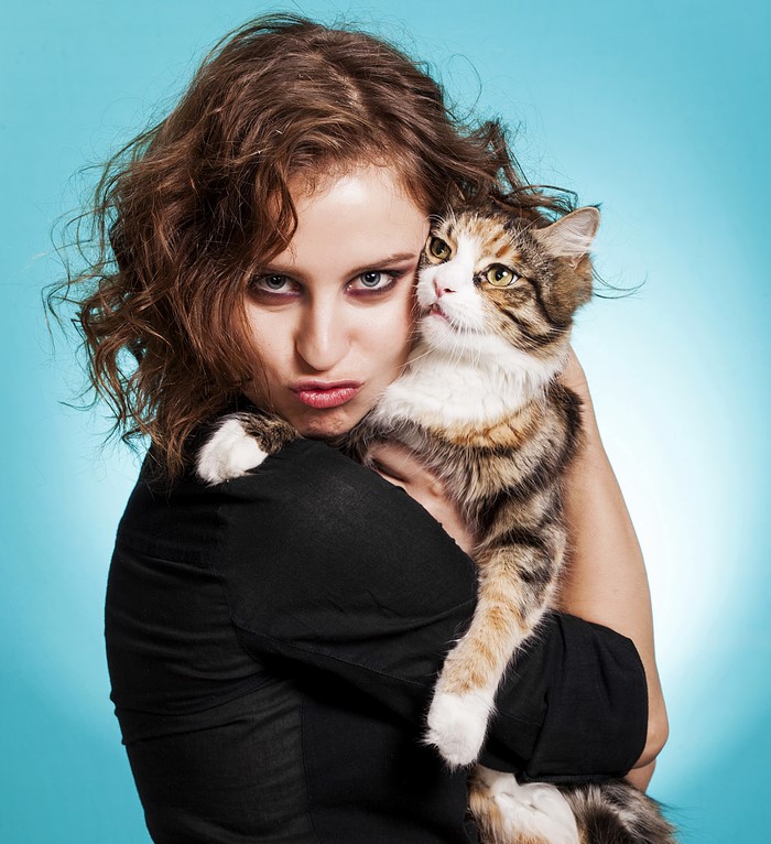 Woman holding a cat with a blue background