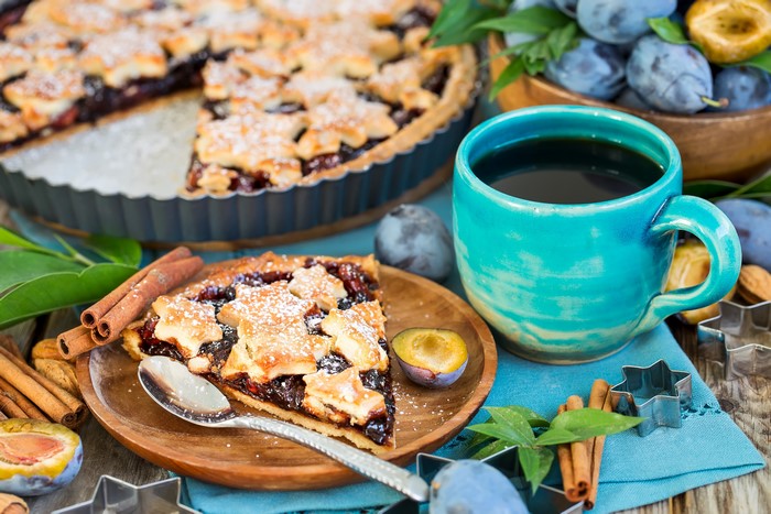 Plum pie slice with coffee and plums