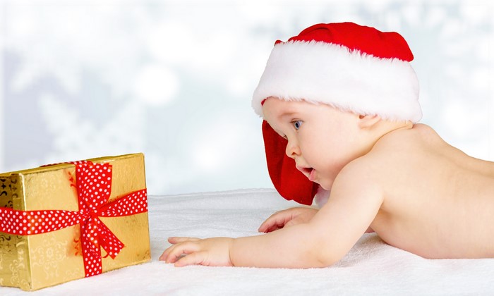 Baby in Santa hat looking at Christmas gift