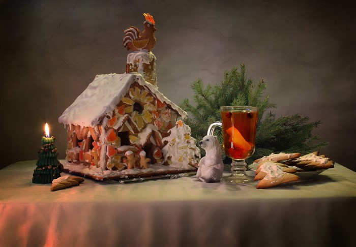 Christmas gingerbread house with candle, drink, and cookies