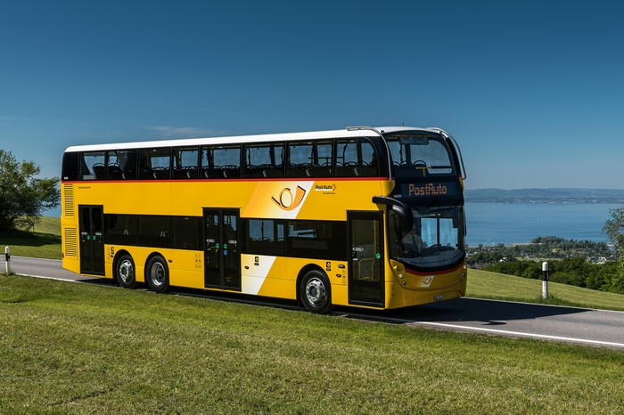 Yellow double-decker PostAuto bus on a road