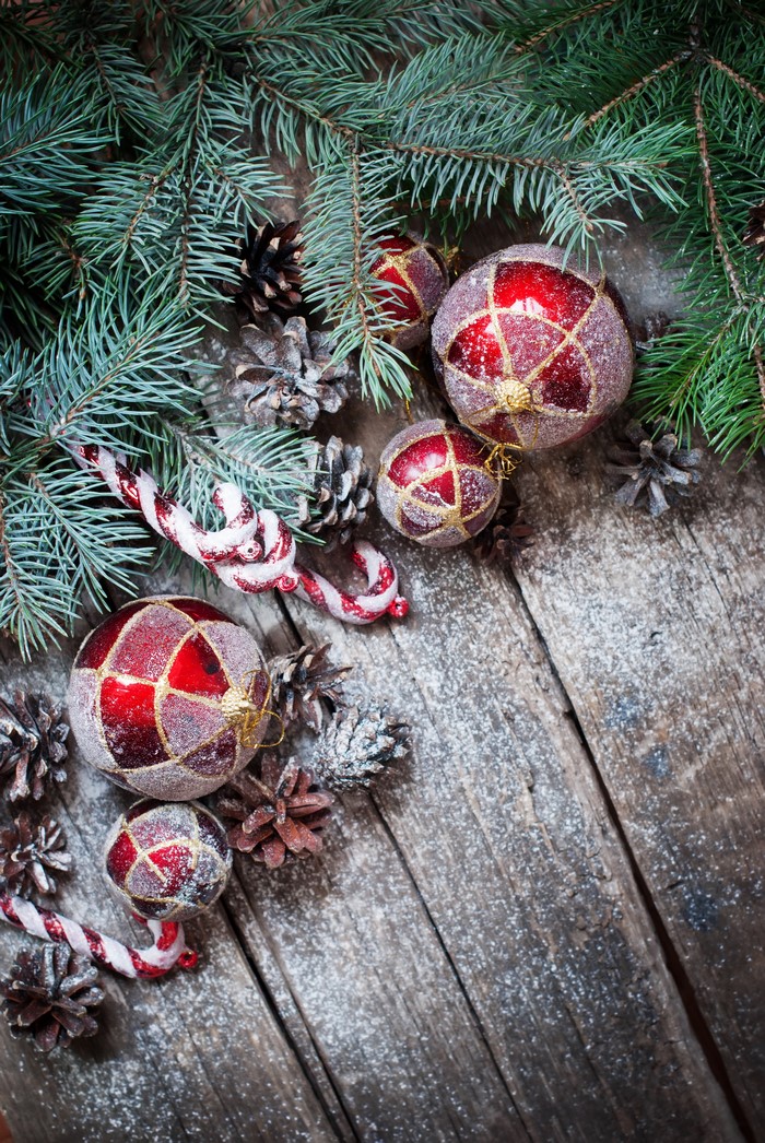 Christmas ornaments, pine cones, and fir branches on wood