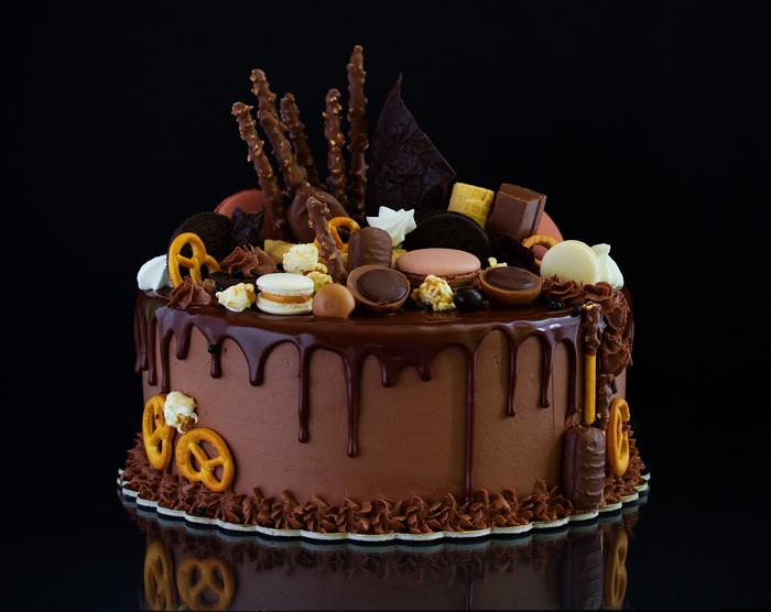 Chocolate drip cake with assorted candies and pretzels