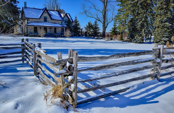Stone house and wooden fence in winter snow in Milton, Ontario, Canada