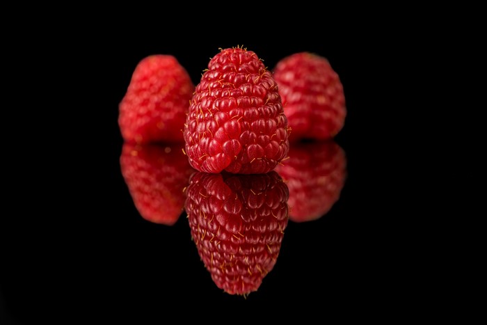 Raspberries with reflection on black background