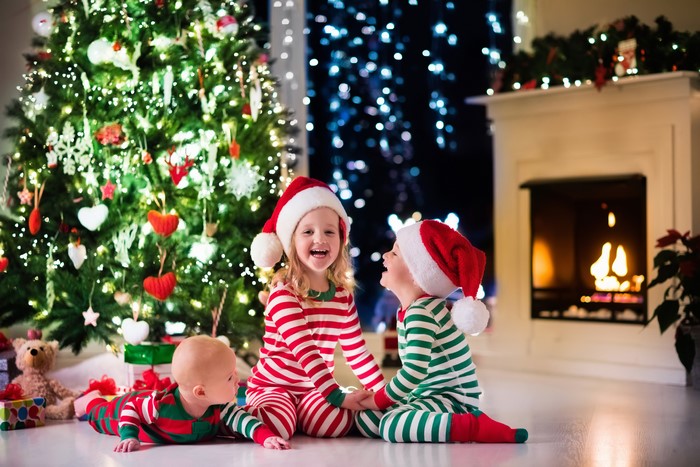 Three Children in Christmas Pajamas by Tree and Fireplace