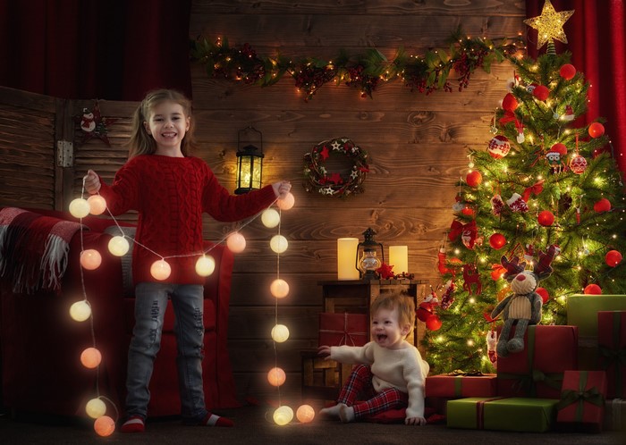 Two Children Decorating a Christmas Tree with Fairy Lights