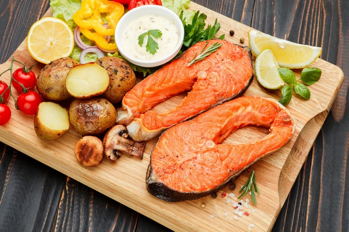 Salmon steaks with potatoes, mushrooms, and vegetables on a cutting board