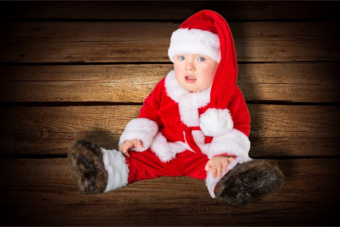 Baby in Santa costume sitting on wood planks