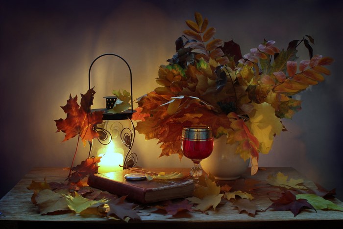 Still-life with lantern, book, wine glass, and autumn foliage