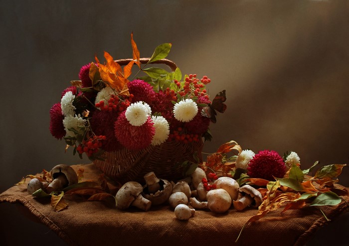 Autumn still-life with asters, berries, mushrooms, and foliage in a wicker basket