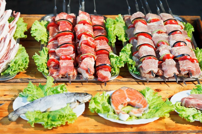 Raw meat skewers, fish, and salmon steaks with lettuce