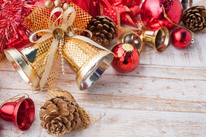 Christmas bells, pine cones, and ornaments on wooden surface