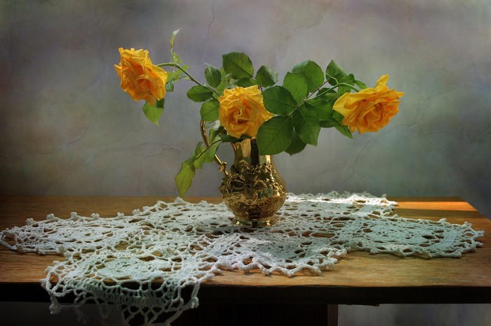 Yellow roses in a golden vase on a table