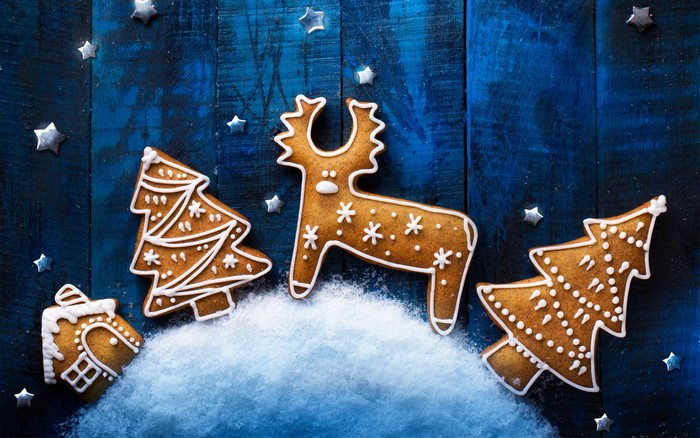 Christmas gingerbread cookies with deer and trees on blue wood