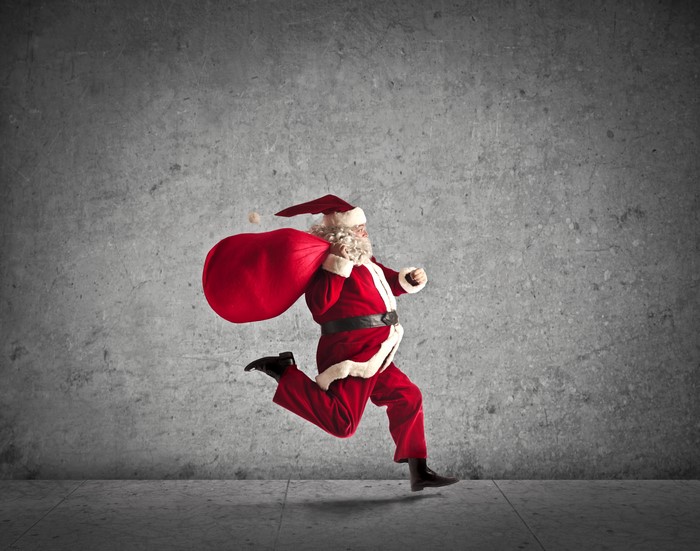 Santa Claus running with a gift bag