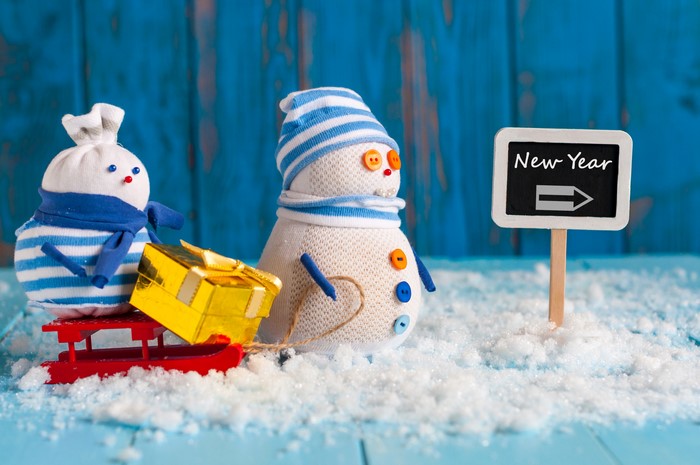 Two sock snowmen with a gift on a sled