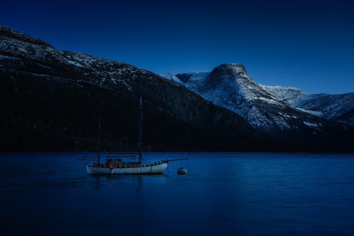 Boat on a lake in front of snowy mountains at night