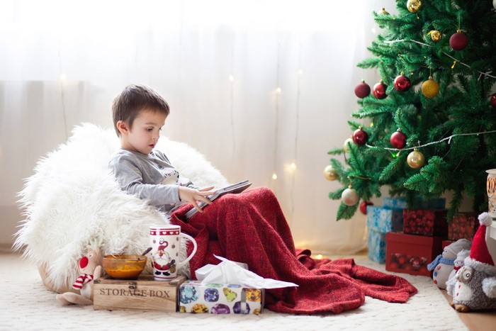 Boy sitting by Christmas tree with tablet