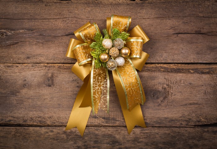 Gold Christmas bow with ornaments on wood