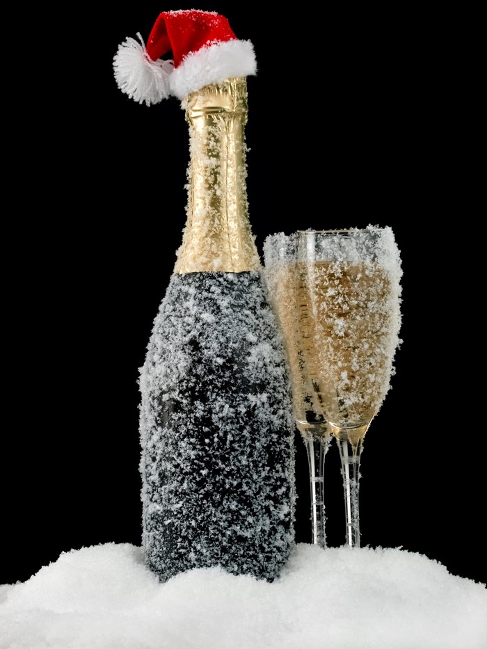 Champagne bottle and glasses with snow and Santa hat