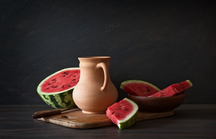 Watermelons and a jug on a cutting board