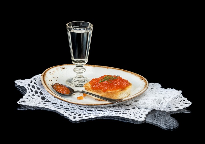 Vodka shot glass with caviar on toast and spoon