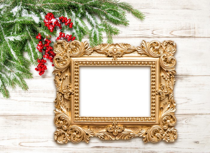 Christmas fir branches with berries and ornate golden frame on wood planks