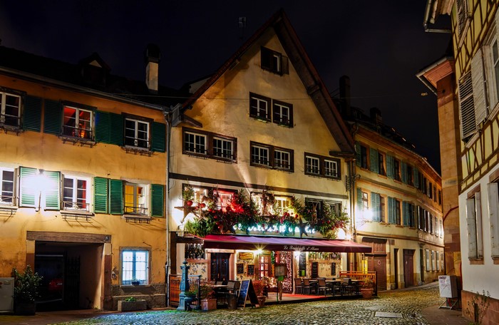 Christmas decorated cafe on a cobblestone street at night in Strasbourg, France